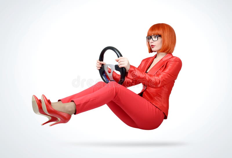 Young redhead woman in red suit driver car with steering wheel, auto concept royalty free stock image Young redhead woman in red suit driver car with steering wheel, auto concept royalty free stock image