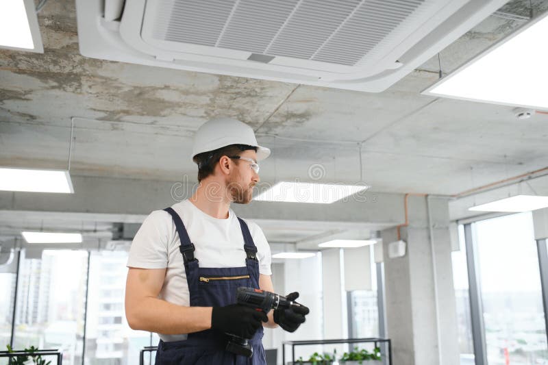 Young Repairman Repairing Ceiling Air Conditioning Unit Stock Image