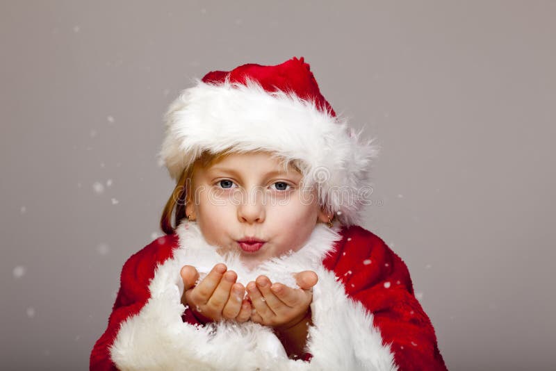 Young santa claus girl blows snow flakes from palm