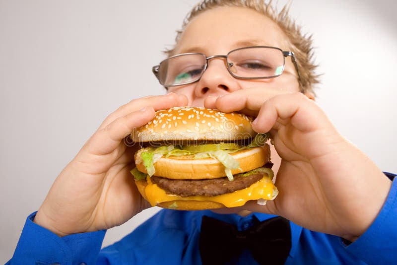Young school boy eating hamburger