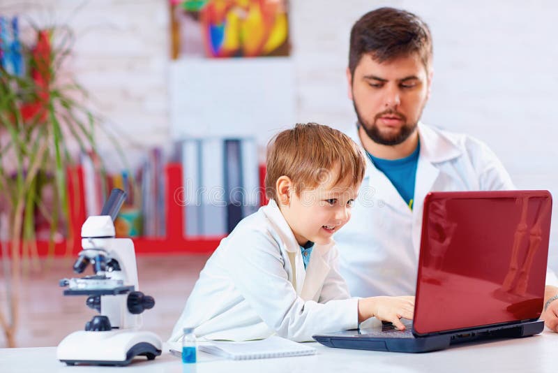 Young scientist conducts experiment on notebook with the help of teacher royalty free stock image
