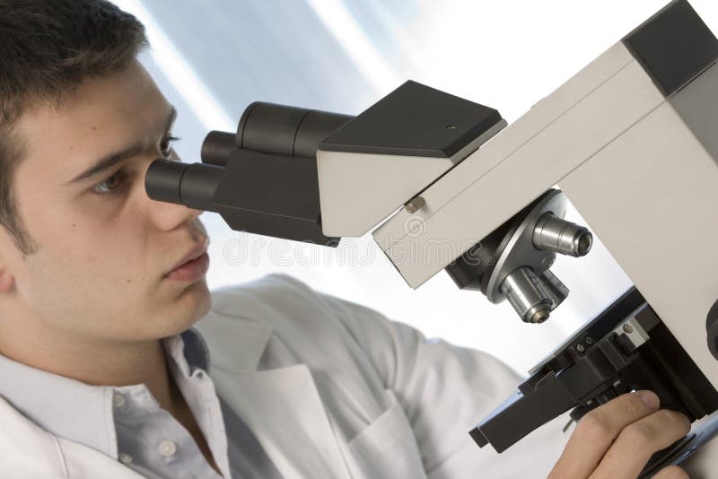 Young scientist watching inside a microscope