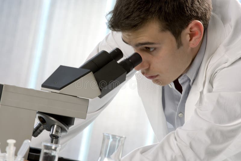 Young scientist watching inside a microscope