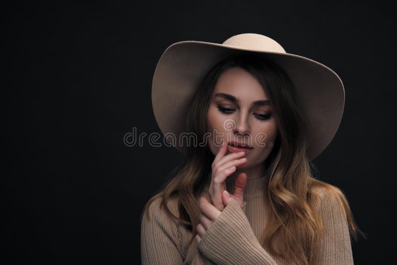 A young sensual sexy woman with a beautiful face and clear natural skin poses in the studio against a black background