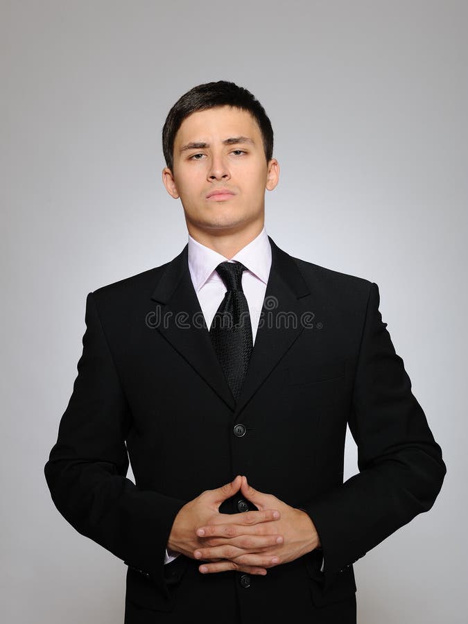 Young serious business man in black suit and tie