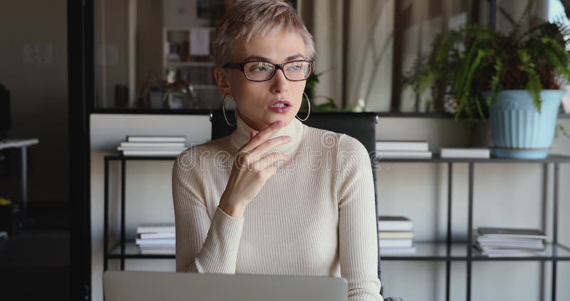 Young serious business woman thinking of business challenge using laptop