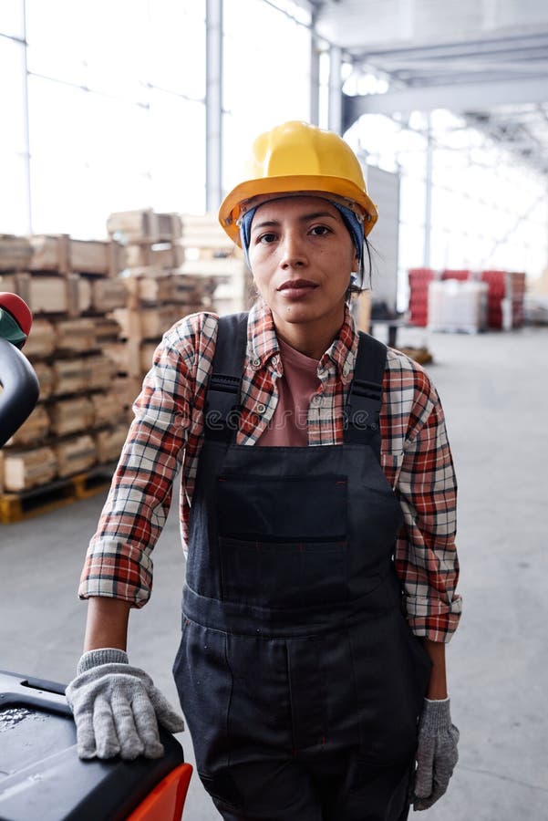 Young Serious Female Engineer in Workwear Standing by Cart with Package