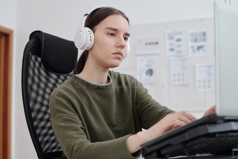 Young serious female programmer decoding data in front of computer monitor royalty free stock image