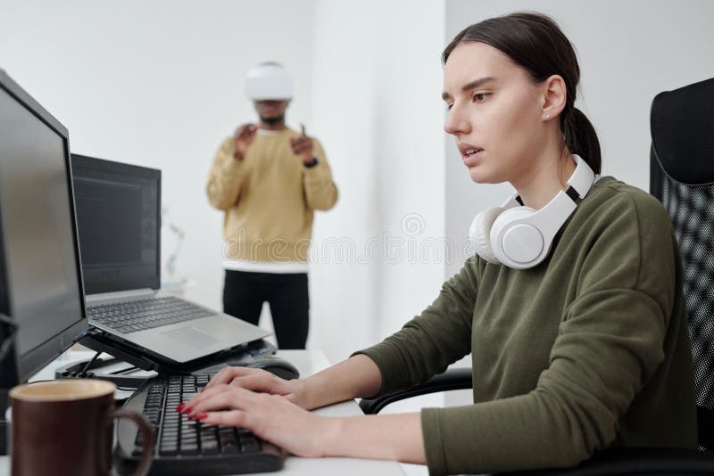 Young serious female programmer decoding data and looking at computer screen stock photography