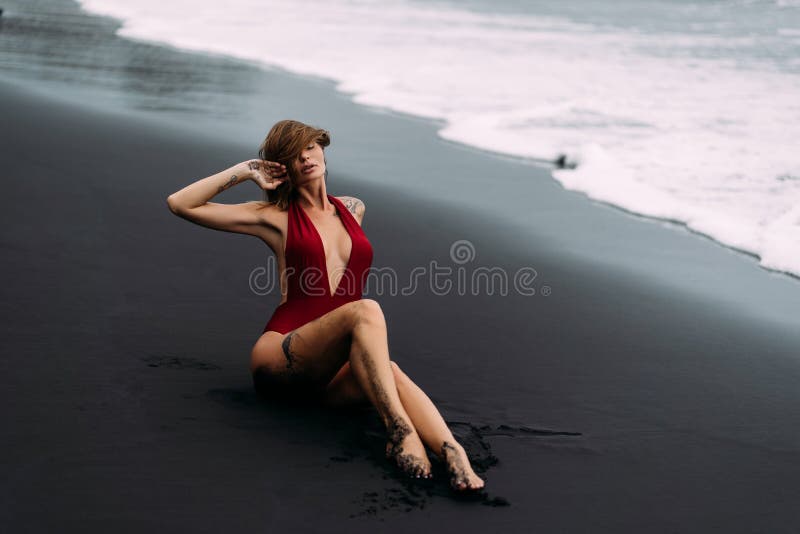 Sexy Girl with Large Breasts Sits on the Sand and Sensually