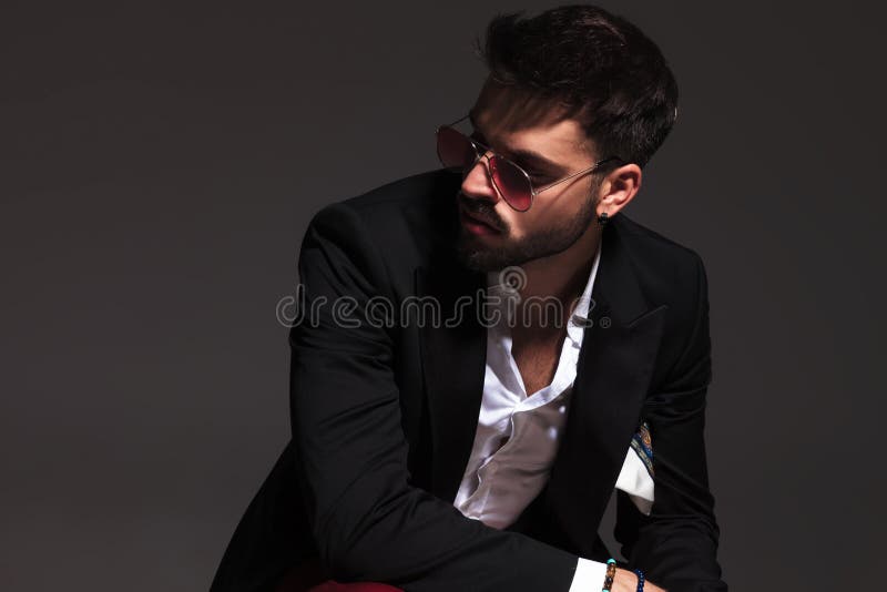 Sexy man in elegant clothes and sunglasses looks to side