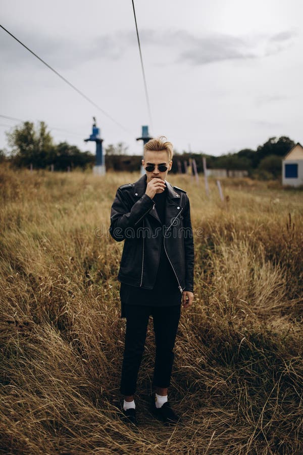 Young sexy man in leather jacket and sunglasses standing outdoor