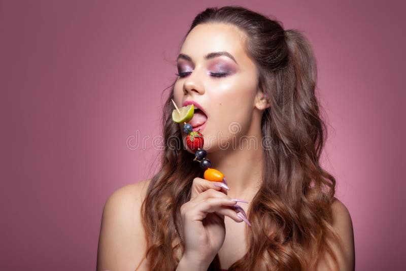 Young sexy woman eating fruit skewer