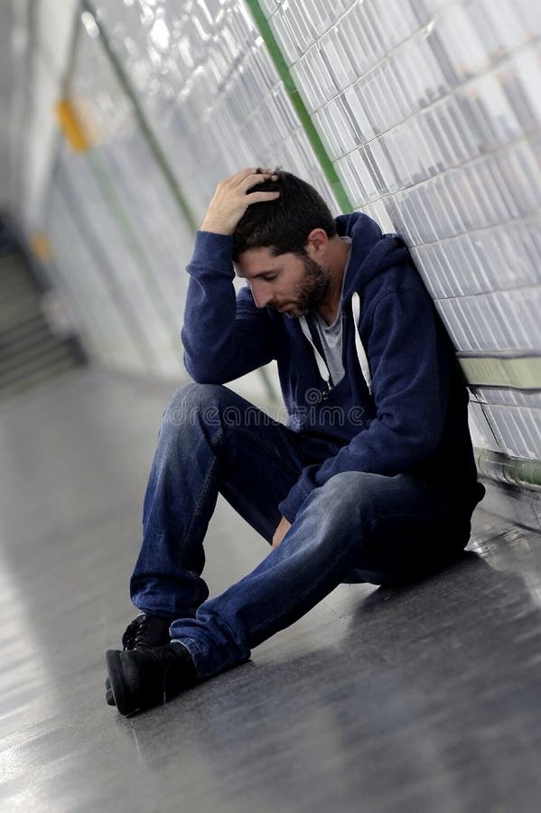 Young sick man lost suffering depression sitting on ground street subway tunnel