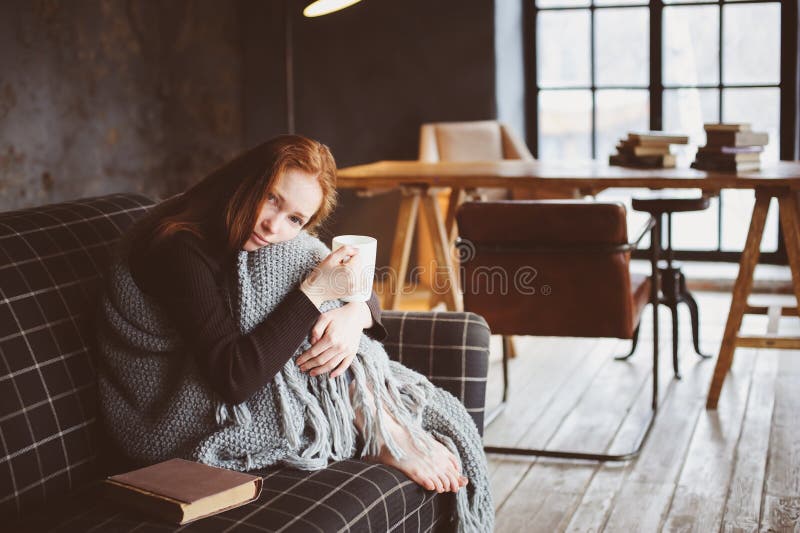 Young sick woman healing with hot drink at home on cozy couch stock photography Young sick woman healing with hot drink at home on cozy couch stock photography