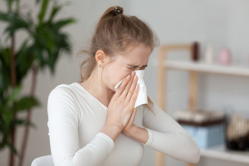 Young sick woman holding handkerchief sneezing indoors royalty free stock photo Young sick woman holding handkerchief sneezing indoors royalty free stock photo