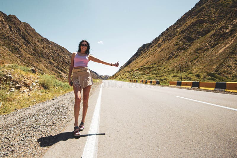 A young single woman of easy virtue, in light sexy clothes, voting on a highway in the desert, traveling alone.