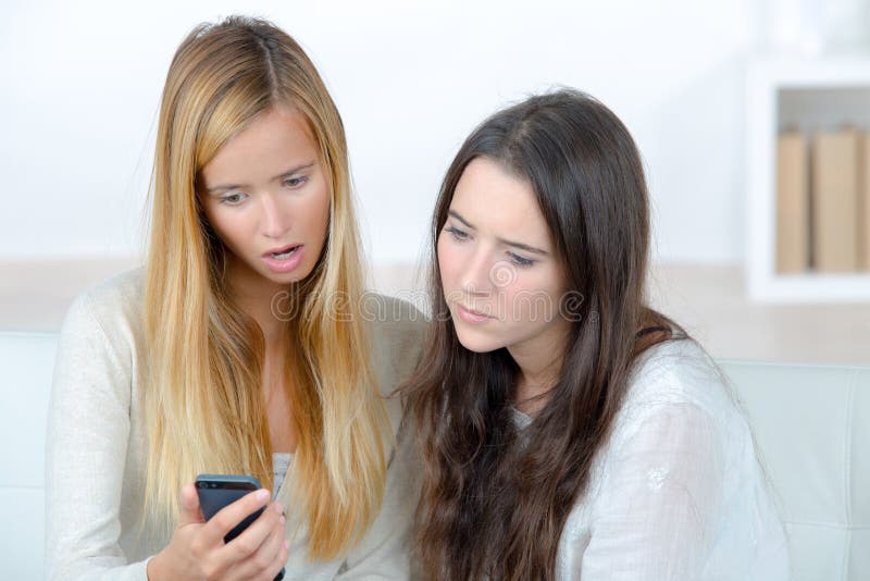 Young sisters looking on phone screen stock images