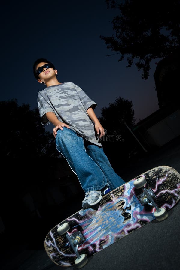 Joven asiático chico afuera en oscuro de pie sobre el pintada cubierto agotador negro gafas de sol.