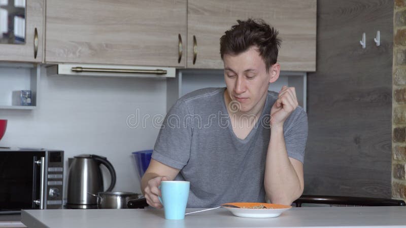 Young sleepy man drinking coffee in the kitchen