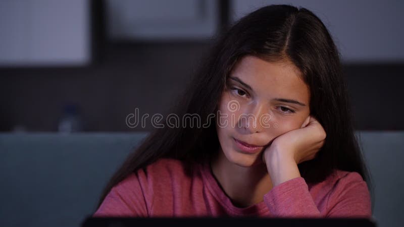 Young sleepy woman looks at black computer display