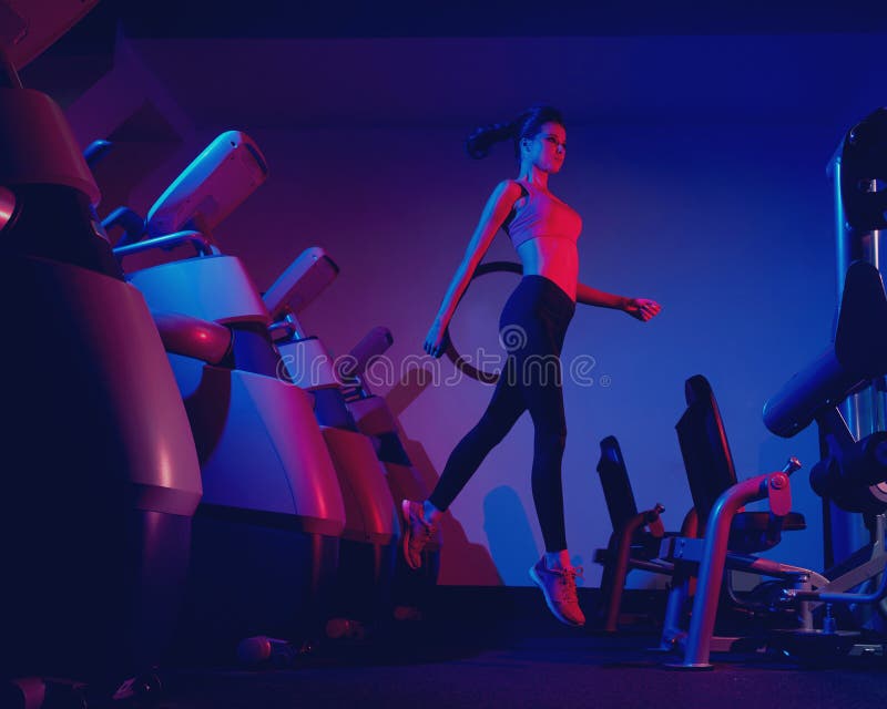 Slim Woman Jumping Between Rows Of Exercise Machines Stock Image