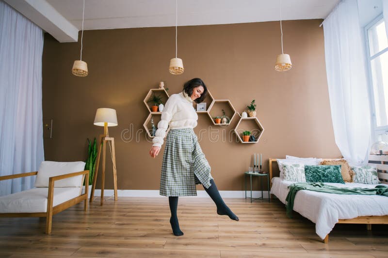 A young smiling woman in white sweater dances in a home room royalty free stock images A young smiling woman in white sweater dances in a home room royalty free stock images