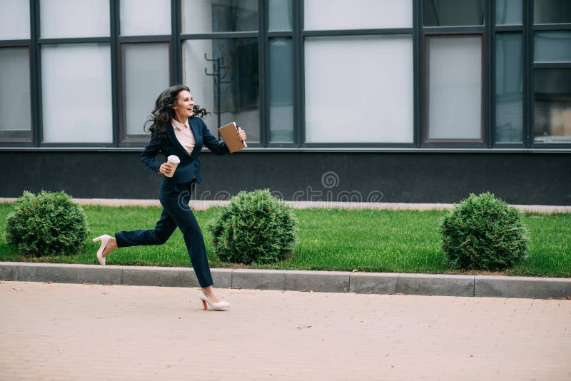 young smiling businesswoman running to work with coffee.