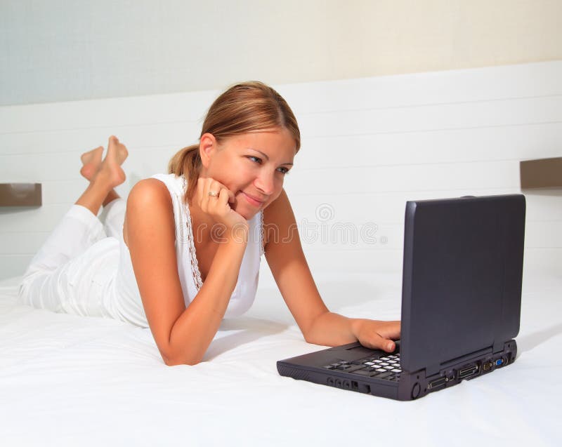 Young smiling businesswoman using laptop in bed