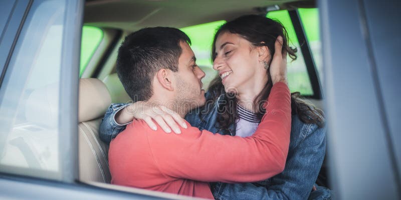 Young smiling and cheerful couple in love, sitting in the back seat