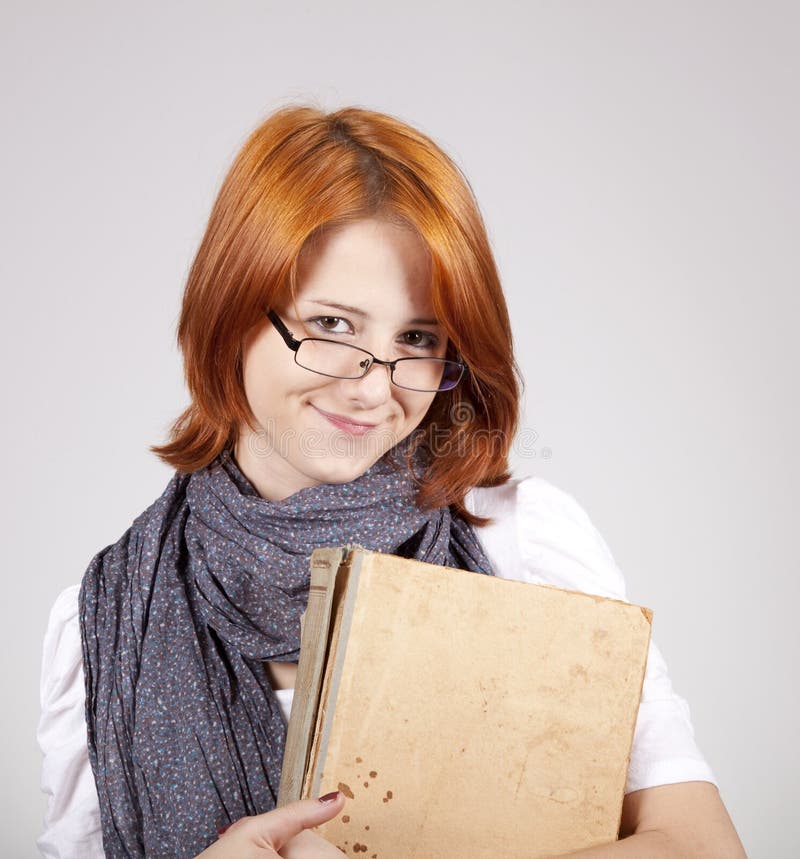 Young smiling girl in glasses with old book