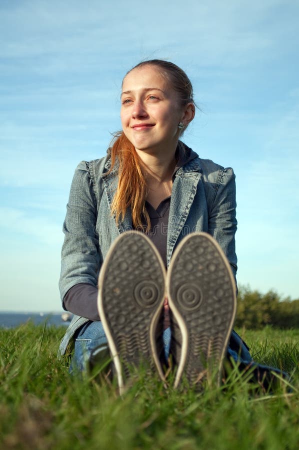 Young smiling girl sitting on the green grass