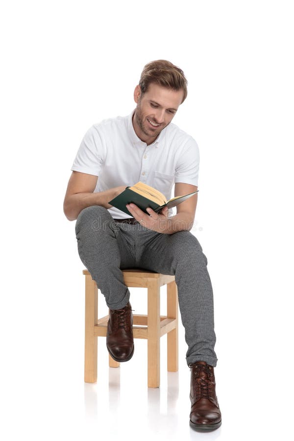 Young smiling seated man read a book on white background