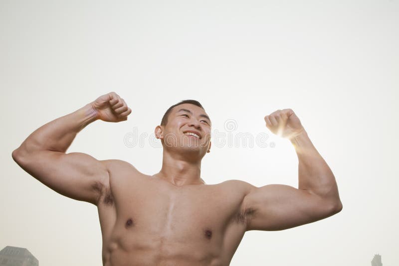 Young, smiling, shirtless young man flexing his muscles with arms raised outdoors in Beijing, China stock photo Young, smiling, shirtless young man flexing his muscles with arms raised outdoors in Beijing, China stock photo