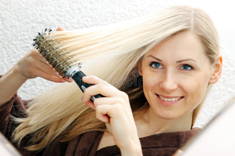 Young smiling woman brushing her long blond hair stock image Young smiling woman brushing her long blond hair stock image
