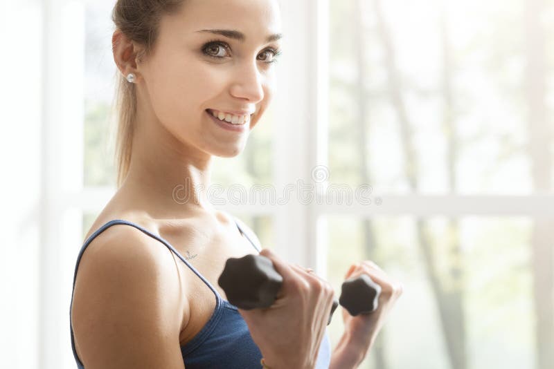 Young sporty woman exercising with dumbbells at home royalty free stock photo Young sporty woman exercising with dumbbells at home royalty free stock photo