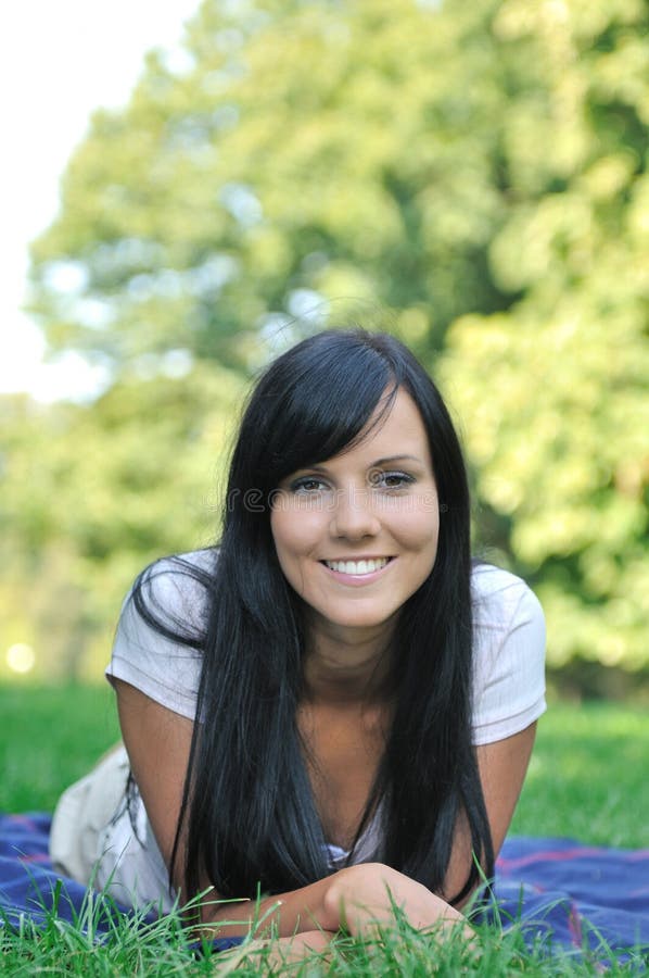 Young smiling woman lying in grass outdoors