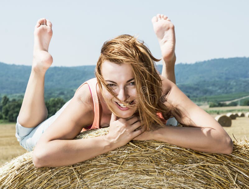 Young smiling woman posing with the stack of straw and enjoying royalty free stock photos Young smiling woman posing with the stack of straw and enjoying royalty free stock photos