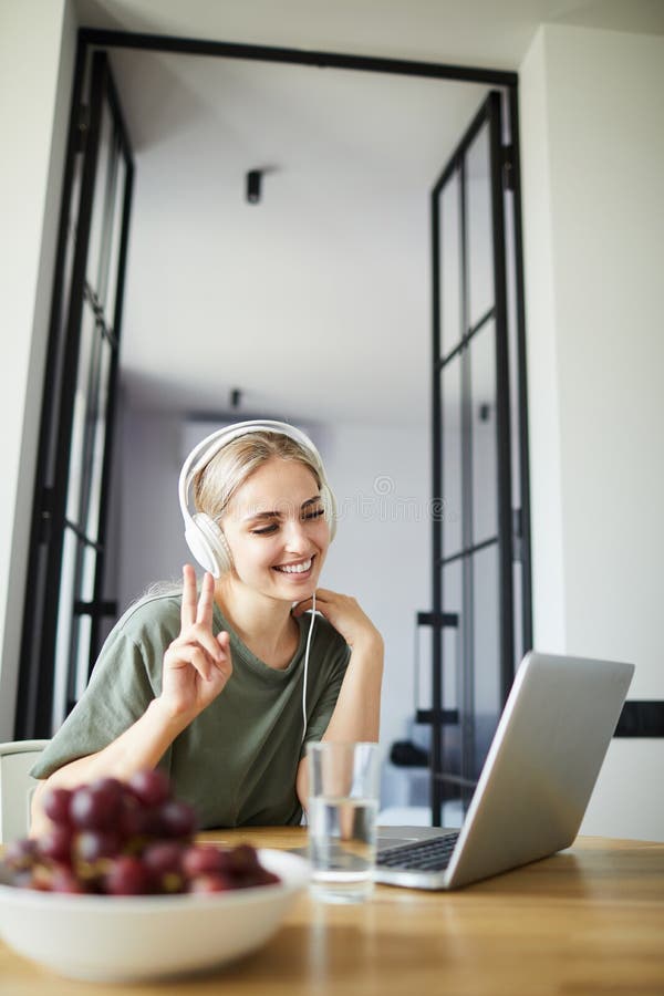 Young smiling woman showing gesture of peace during online communication stock image Young smiling woman showing gesture of peace during online communication stock image