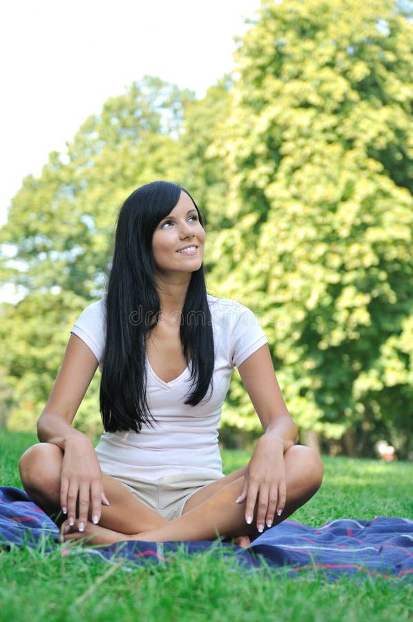 Young smiling woman sitting on rug in park