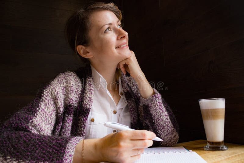 Young smiling woman thinking with pen and open notebook. Thoughtful girl portrait. Journalist and writer concept. Business lifesty stock photography Young smiling woman thinking with pen and open notebook. Thoughtful girl portrait. Journalist and writer concept. Business lifesty stock photography