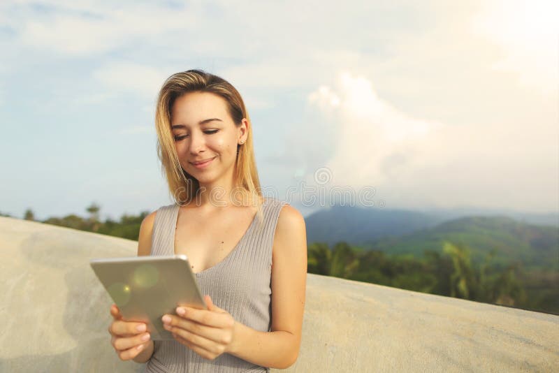 Young smiling woman using tablet with mountains background, Thailand. royalty free stock photography Young smiling woman using tablet with mountains background, Thailand. royalty free stock photography