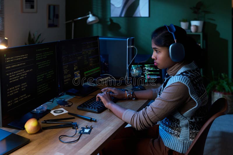 Young South Asian Woman Coding Software on Computer Monitors at Night royalty free stock photography
