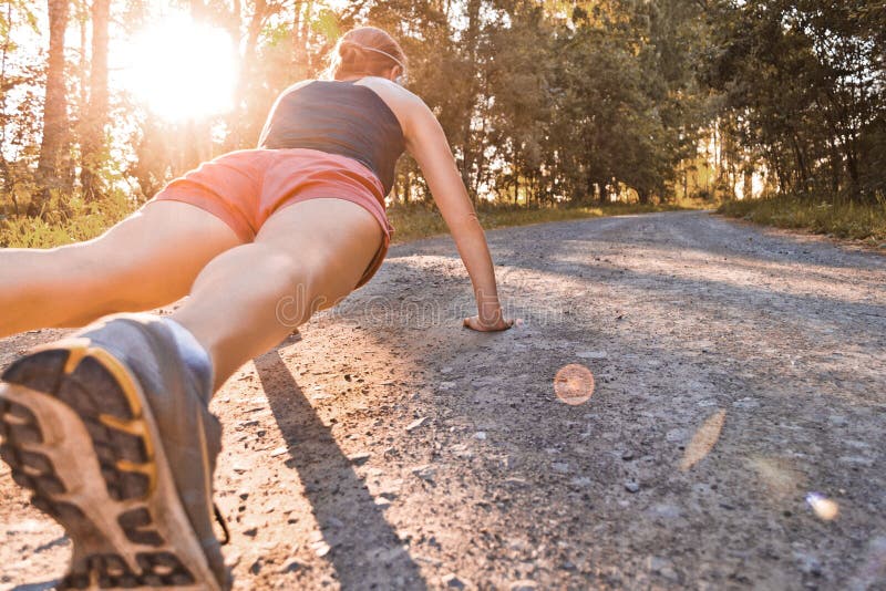 Joven deporte una mujer tiene manivelas sobre el verano Bosque carreteras.