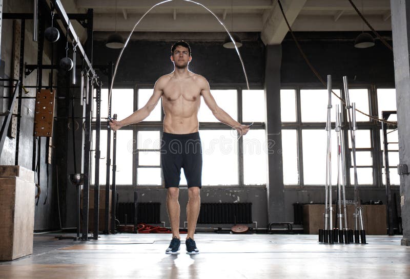 Young sportsman doing jump rope workout in gym.