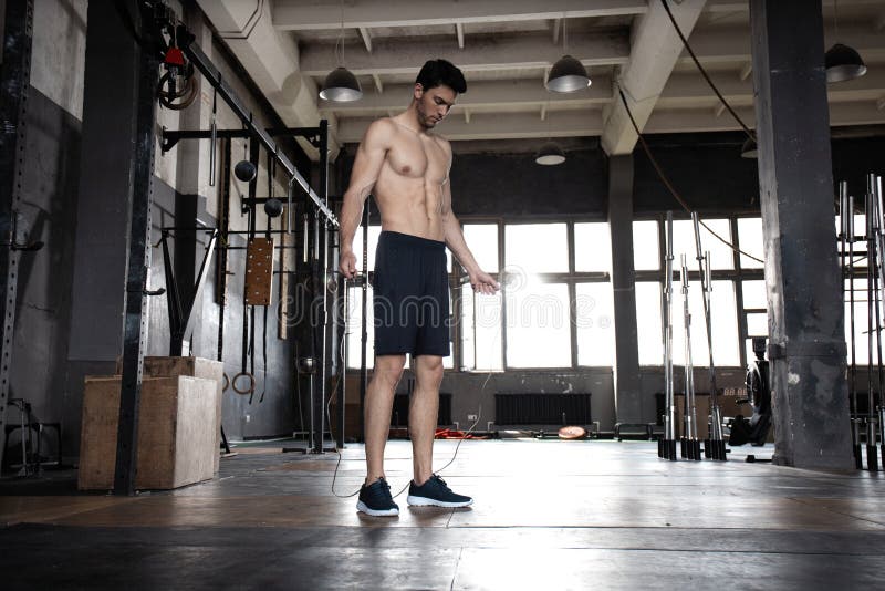 Young sportsman doing jump rope workout in gym.