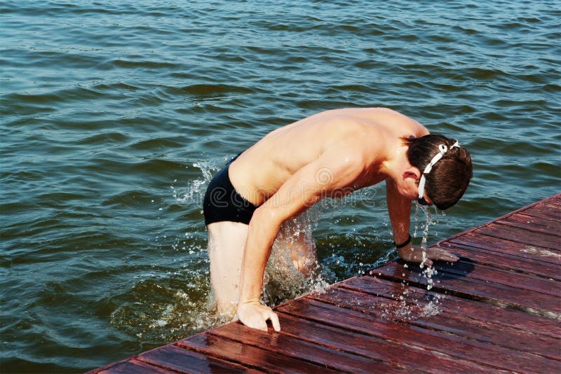 The young sportsman jumps out from water