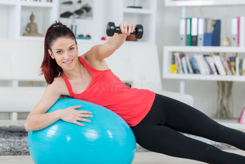 Young sportswoman doing exercises with ball and dumbbells stock image Young sportswoman doing exercises with ball and dumbbells stock image