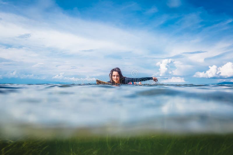 Young Sportswoman in Wetsuit on Surfing Board in Ocean at Nusa Dua