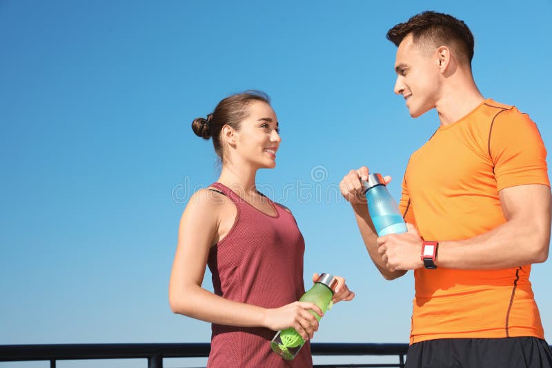 Young sporty couple with bottles of water outdoors on sunny day. stock images Young sporty couple with bottles of water outdoors on sunny day. stock images
